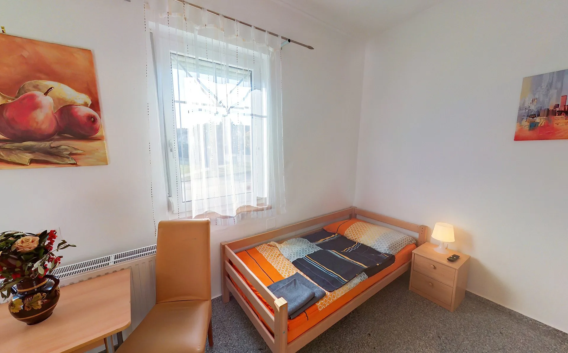Helles Einzelzimmer mit Bett, Schreibtisch und Sitzgelegenheit